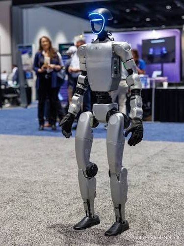 Humanoid robot walking an exhibition floor past visitors