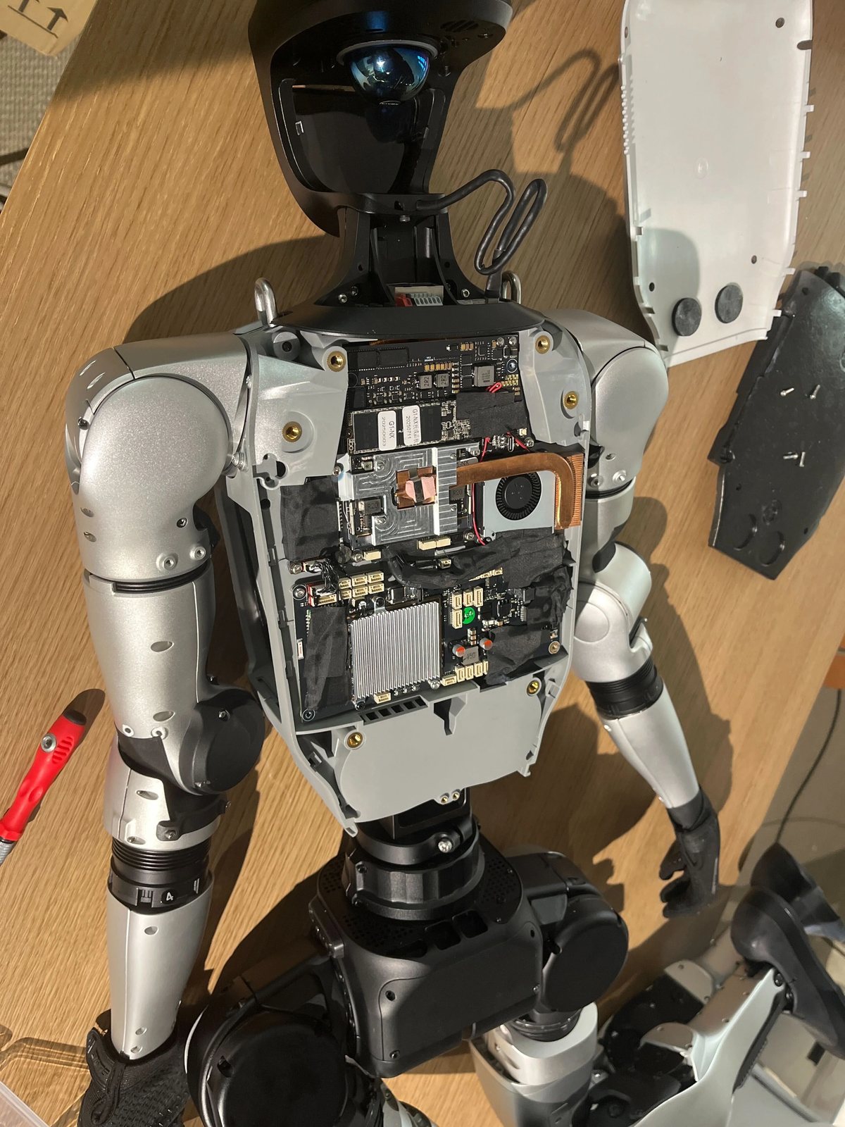Unitree G1 humanoid robot opened on a workbench, showing its computer boards and cooling